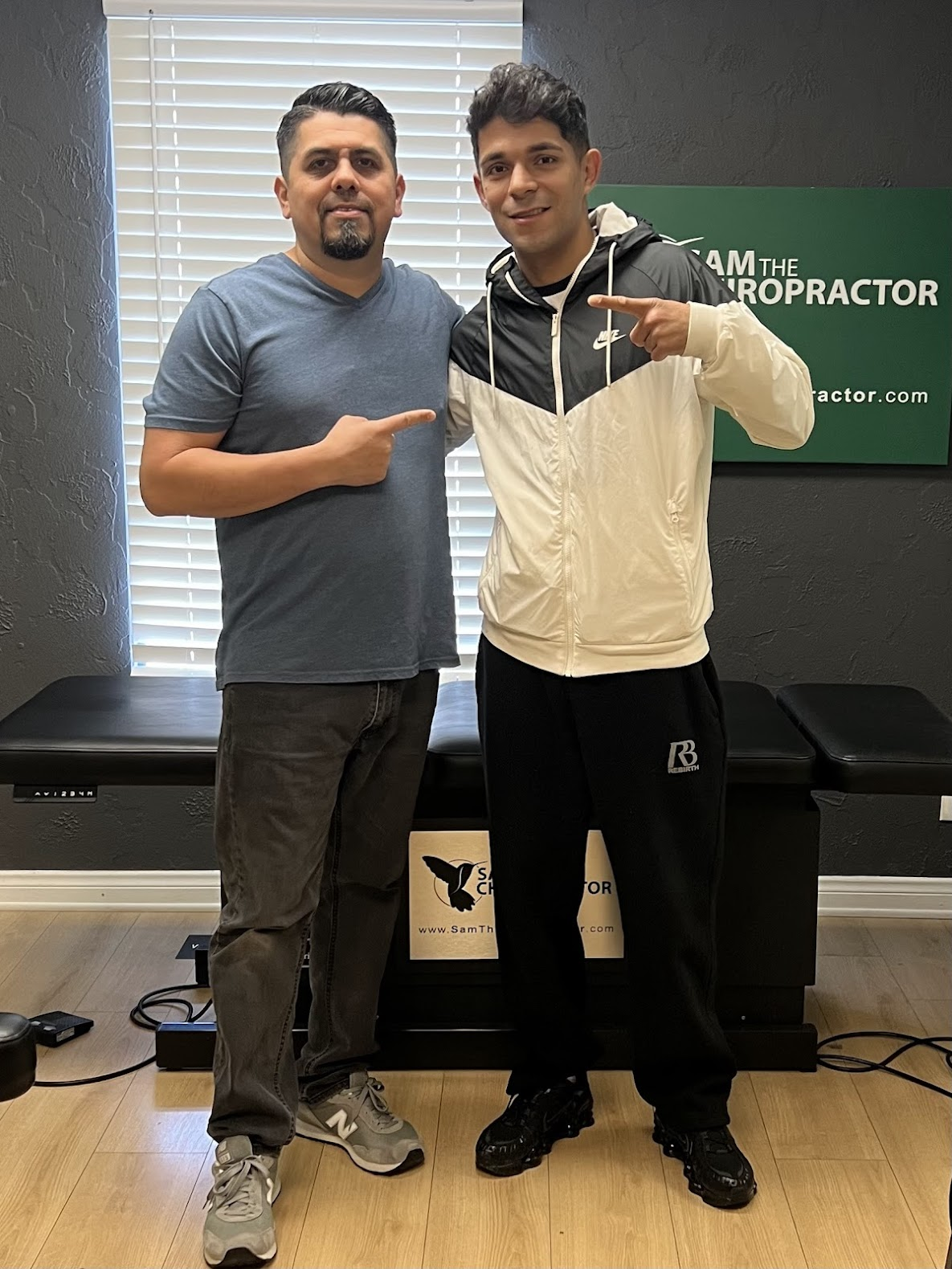 Dr. Sam with a happy patient pointing each other out after the adjustment